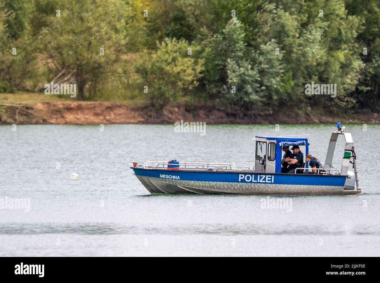 Porta Westfalica, Germania. 27th luglio 2022. Una barca della polizia passa una boa che segna un punto in un laghetto di ghiaia dove due persone non sono riuscito a surfare per motivi inspiegabili mentre nuotavano domenica (24 luglio 2022). Secondo un portavoce del dipartimento dei vigili del fuoco, alcune parti del lago sono profonde circa 30 metri. Gli esperti della polizia ora vogliono cercare le due persone con una sonda subacquea. Credit: Lino Mirgeler/dpa/Alamy Live News Foto Stock