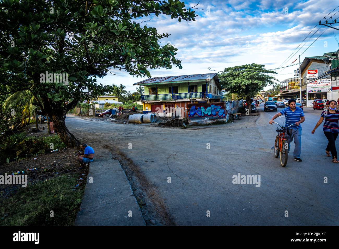 Un colpo di gente che cammina e guida una bicicletta sul bivio contro gli edifici colorati in Costa Rica Foto Stock