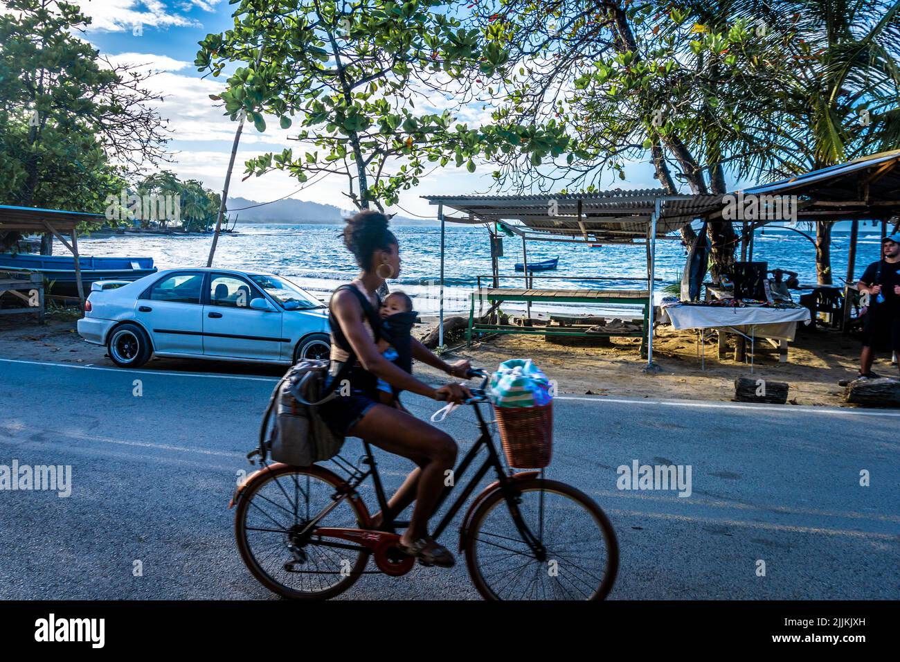 Un colpo di una donna che guida una bicicletta sulla strada contro il mare in Costa Rica Foto Stock