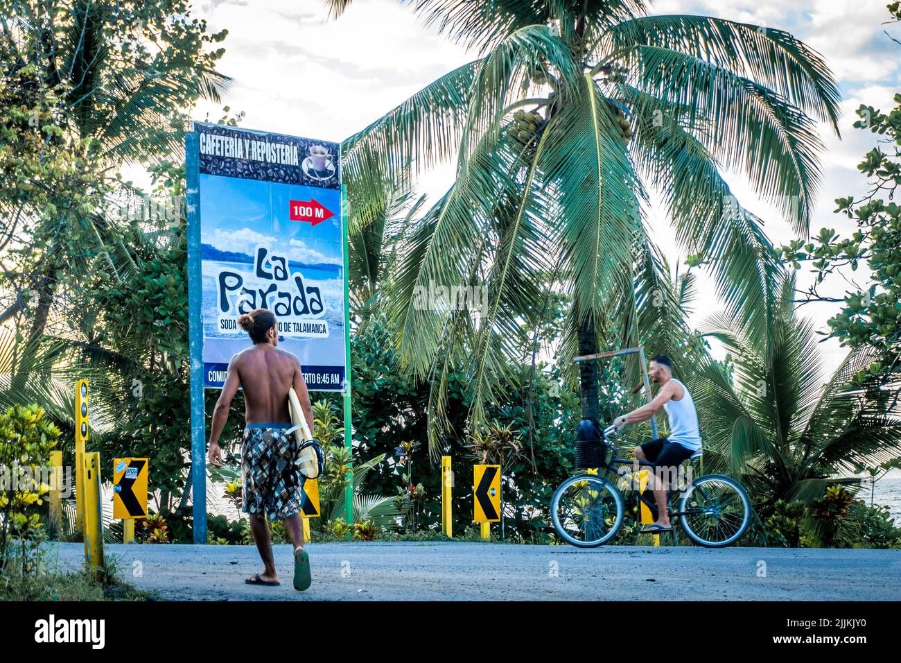 Un colpo di gente che cammina e guida una bicicletta sulla strada contro le palme in Costa Rica Foto Stock