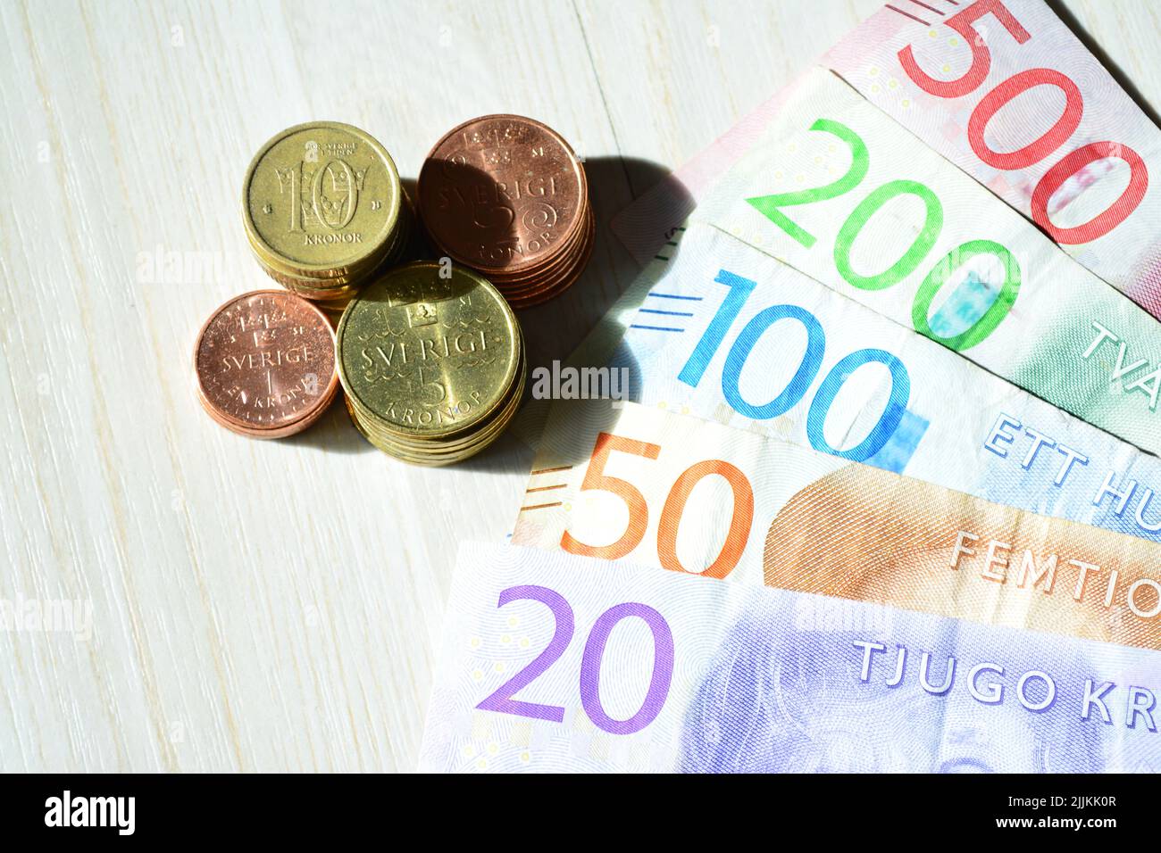 Un primo piano di banconote e monete in valuta svedese (Krona) su una superficie di legno Foto Stock