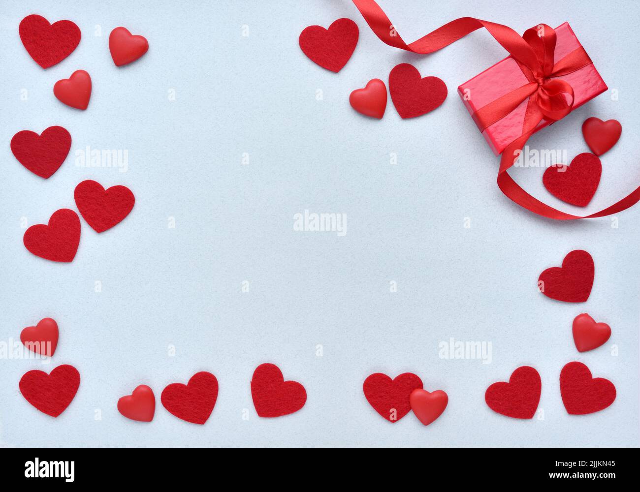 San Valentino sfondo. Confezione regalo rossa con nastro e cuori su sfondo blu pastello. Vista dall'alto Foto Stock