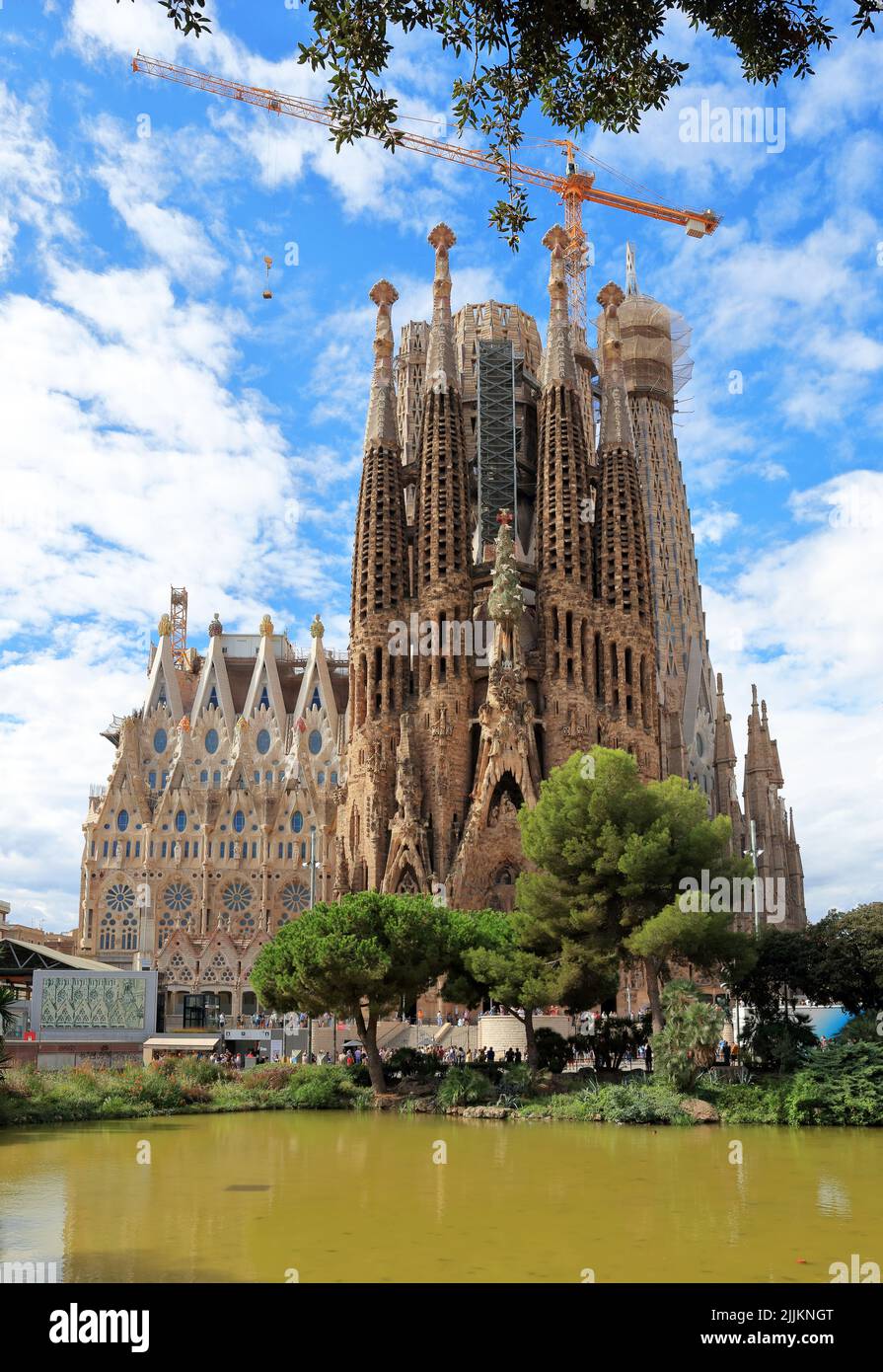 Un primo piano della 'vecchia facciata' della Sagrada Familia e del lago nel parco di fronte Foto Stock