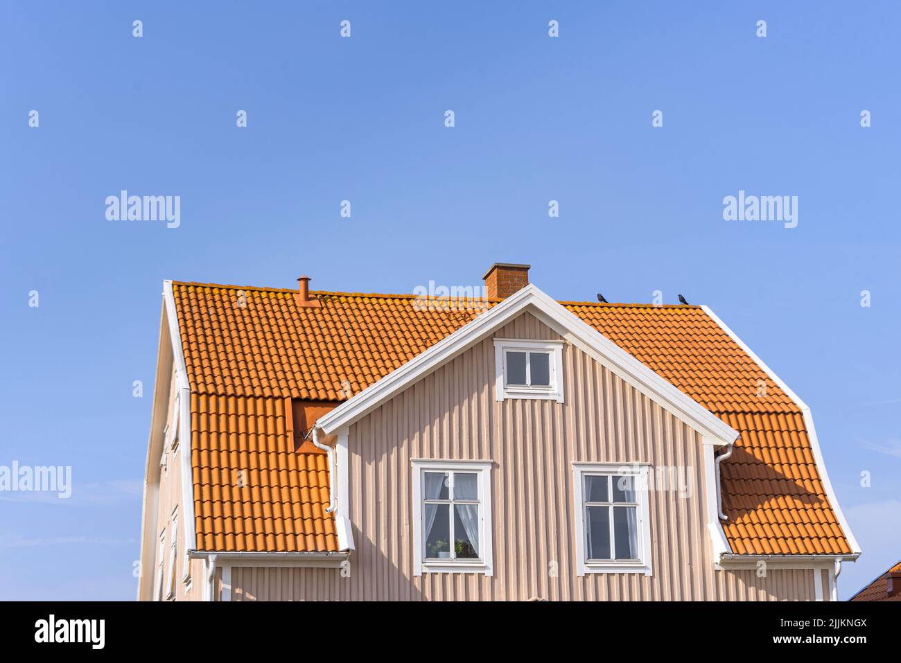 Un angolo basso di una casa rosa e arancione contro un cielo blu senza nuvole in una giornata di sole Foto Stock