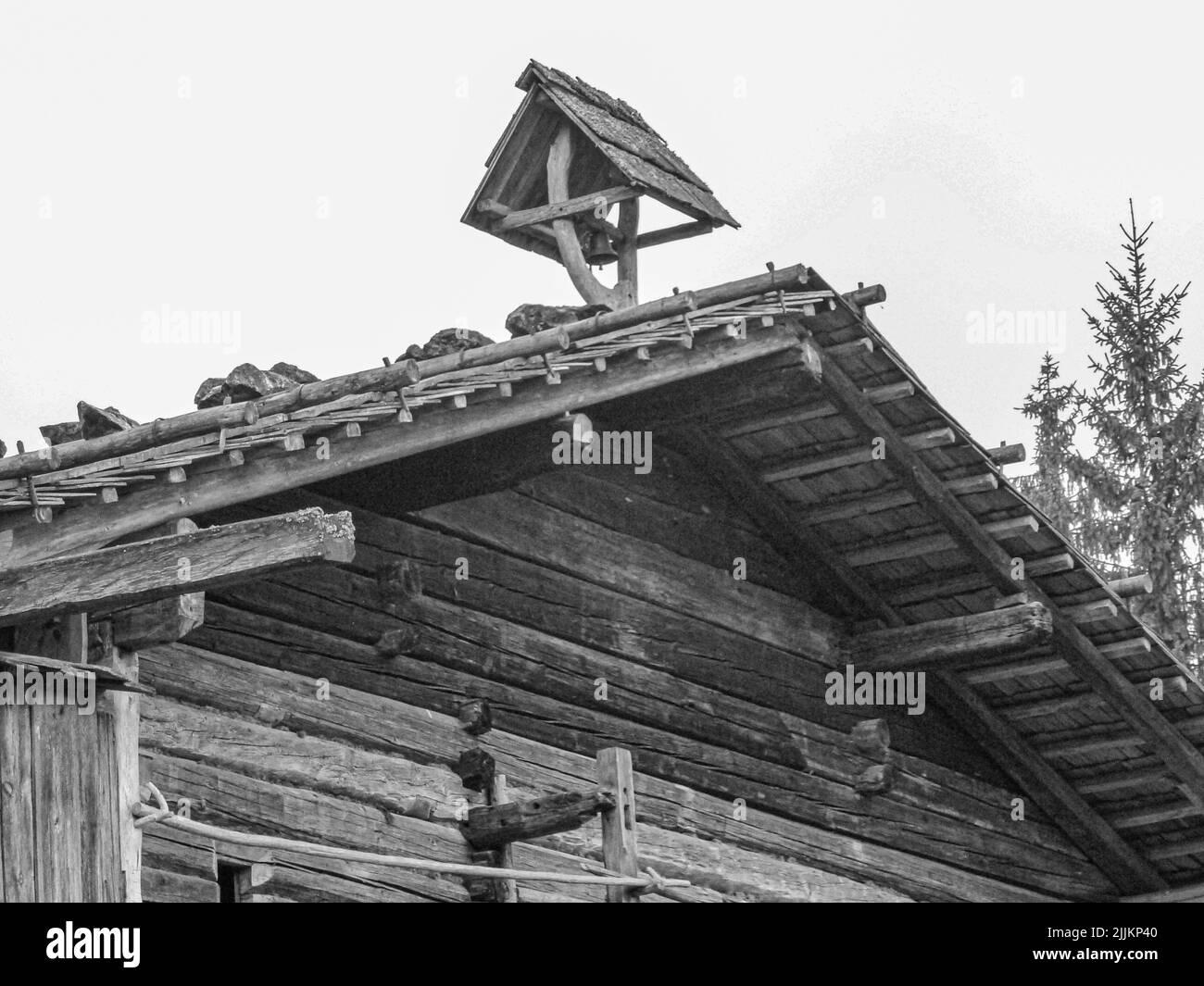 Una foto in scala di grigi di un edificio in legno con alberi sullo sfondo Foto Stock