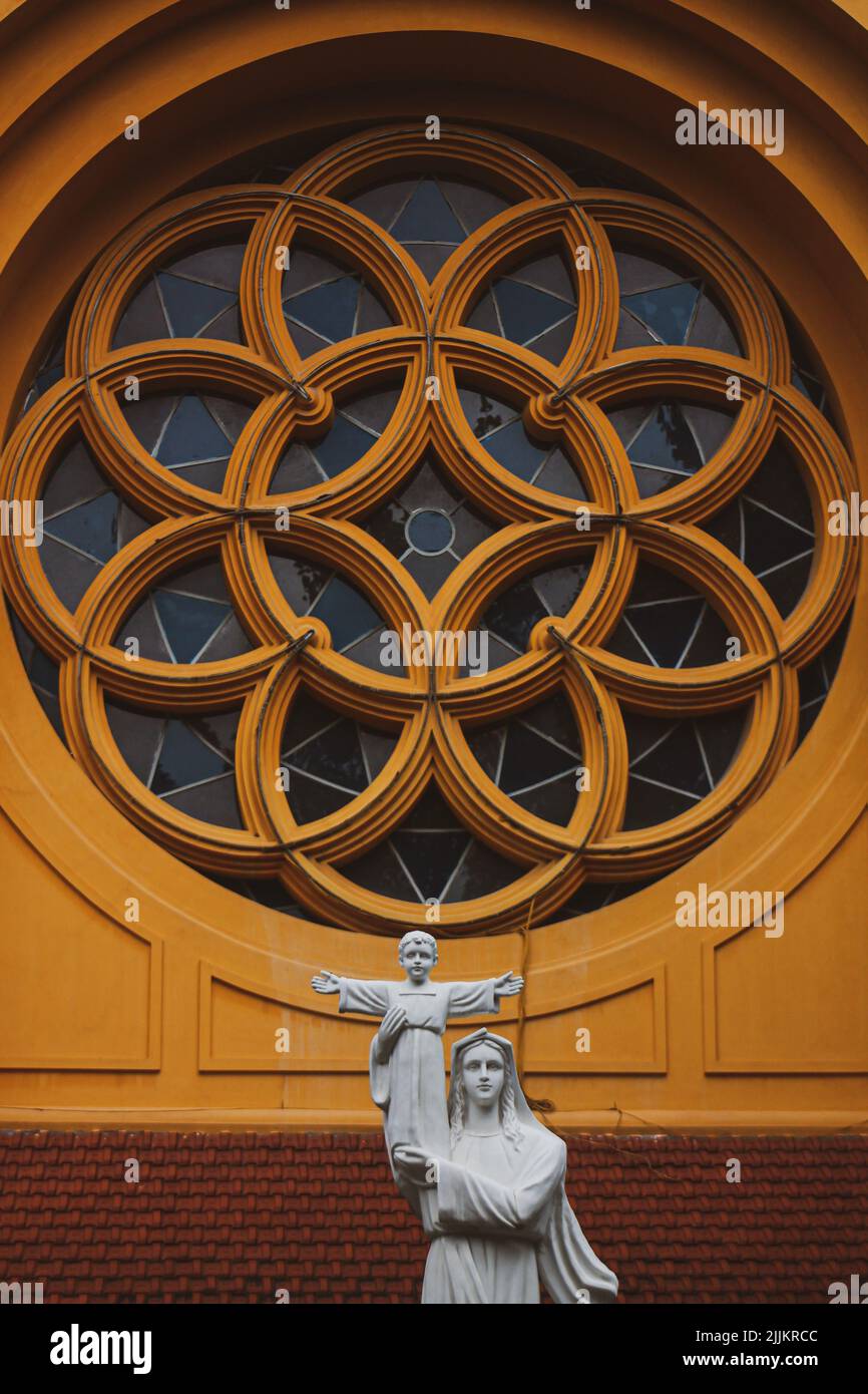Una statua cattolica accanto ad una vetrata circolare, Vietnam Foto Stock