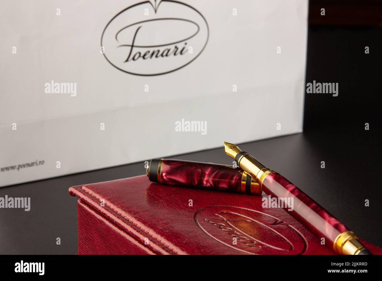 Primo piano di una penna rossa con un pennino dorato sulla scatola Foto Stock