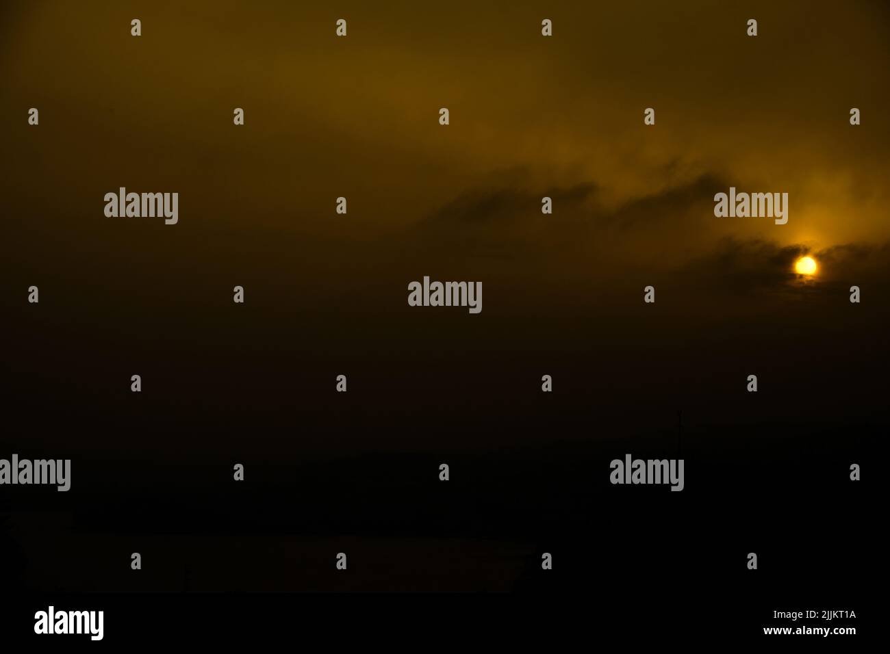 Cielo di tramonto Moody e nuvole scure con un profondo sole arancione in un ambiente tempestoso. Nuvole illuminate e presenza minacciosa. Atmosfera e mistero. Foto Stock
