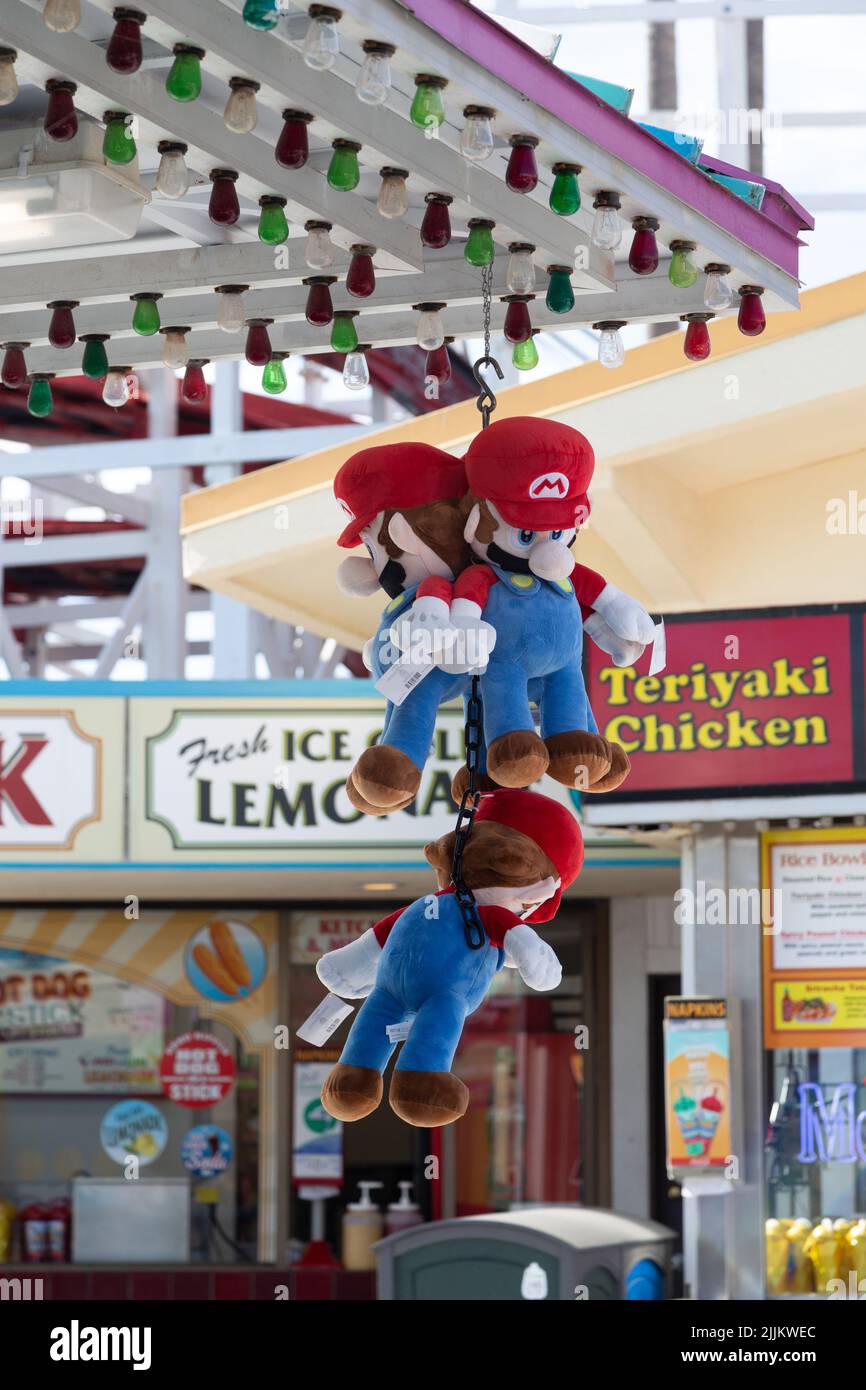 Un colpo verticale di giocattoli imbottiti Mario appesi su un palco del lungomare come un premio Foto Stock