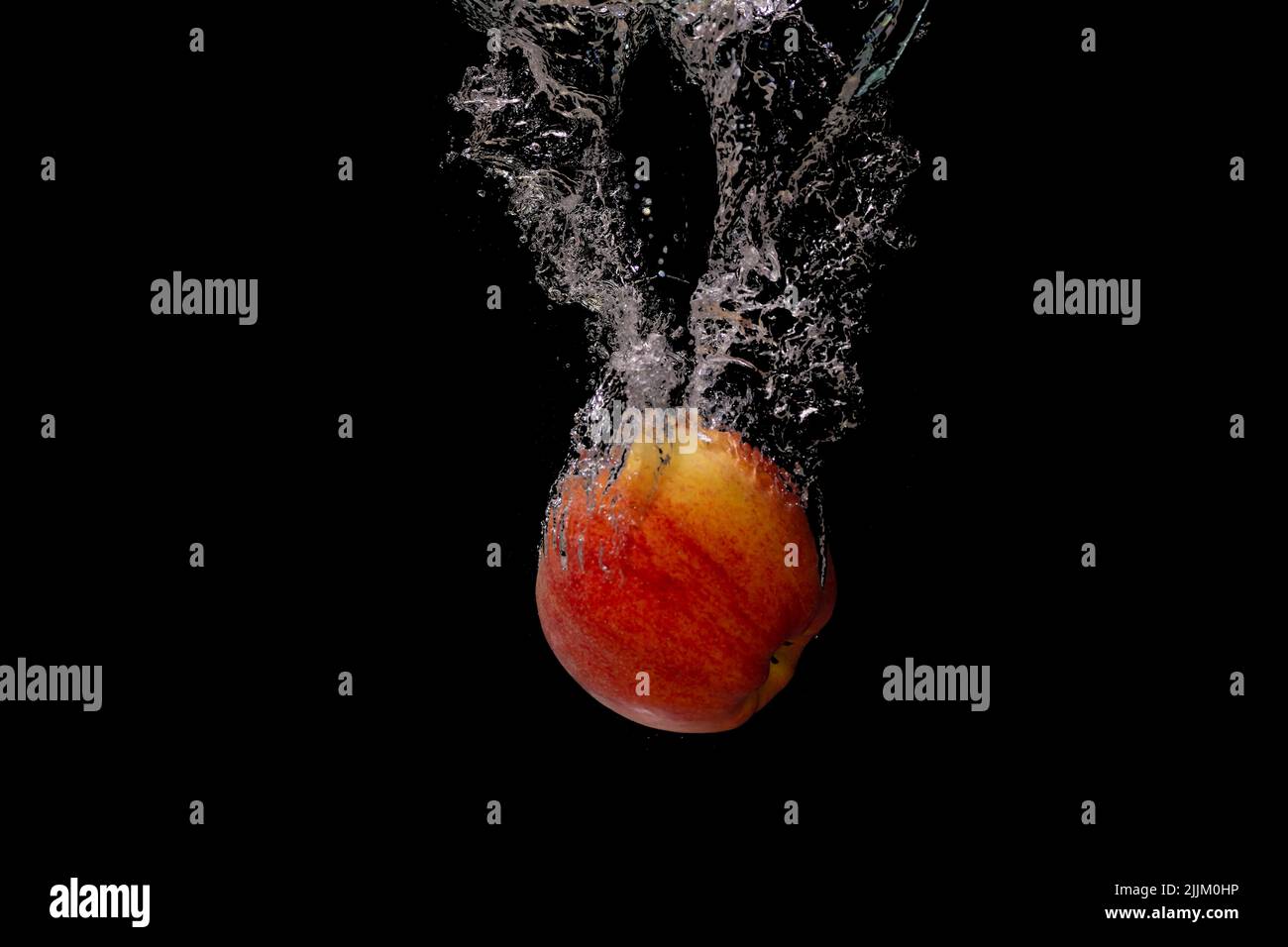 Una pesca che spruzzi su acqua isolato su sfondo nero Foto Stock