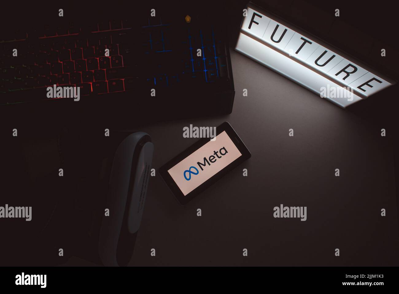 Il concetto di rebranding di Facebook con un logo Meta su uno schermo del telefono accanto alla scrittura futura in una scatola luminosa e una tastiera Foto Stock