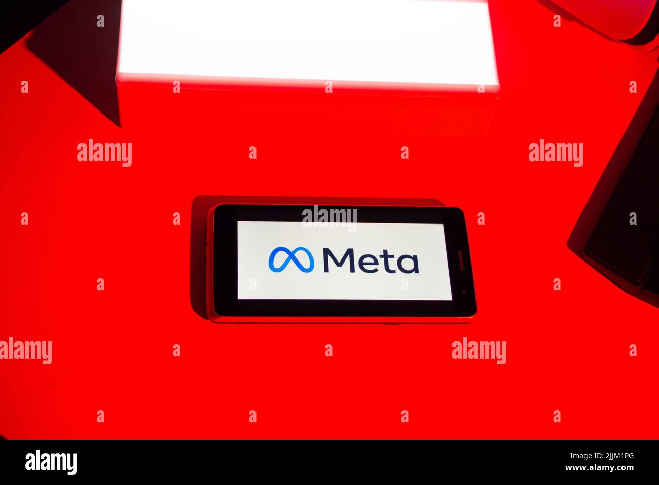 Primo piano di un logo Meta sullo schermo di un telefono cellulare su sfondo rosso Foto Stock