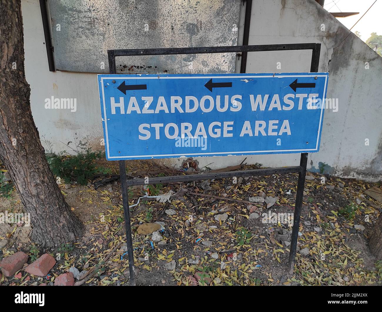 Un cartello blu con la scritta "Hazardous Waste Storage Area" e frecce nere a sinistra in Gujarat Sanand GIDC Automobile Factory Foto Stock