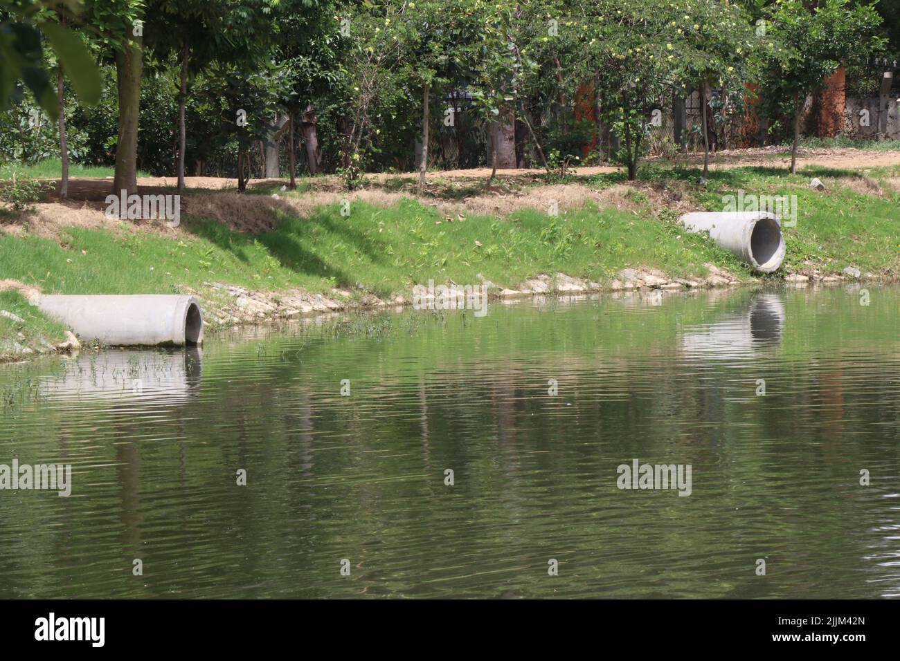 I tubi di drenaggio in calcestruzzo sono installati sopra la superficie di un lago per impedire l'eccessivo riempimento di acqua piovana nel lago Foto Stock