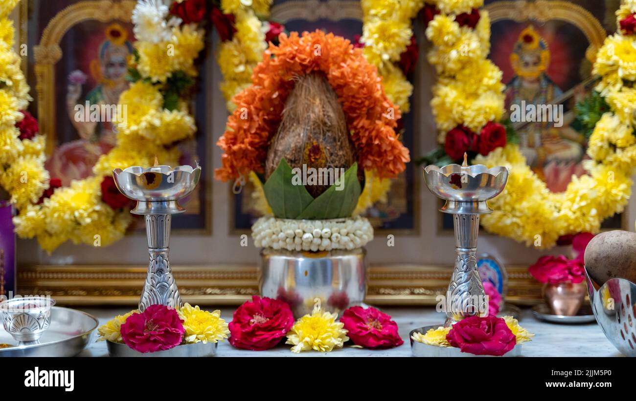 Alcuni oggetti di culto tradizionali indiani su un tavolo decorato con fiori. Foto Stock