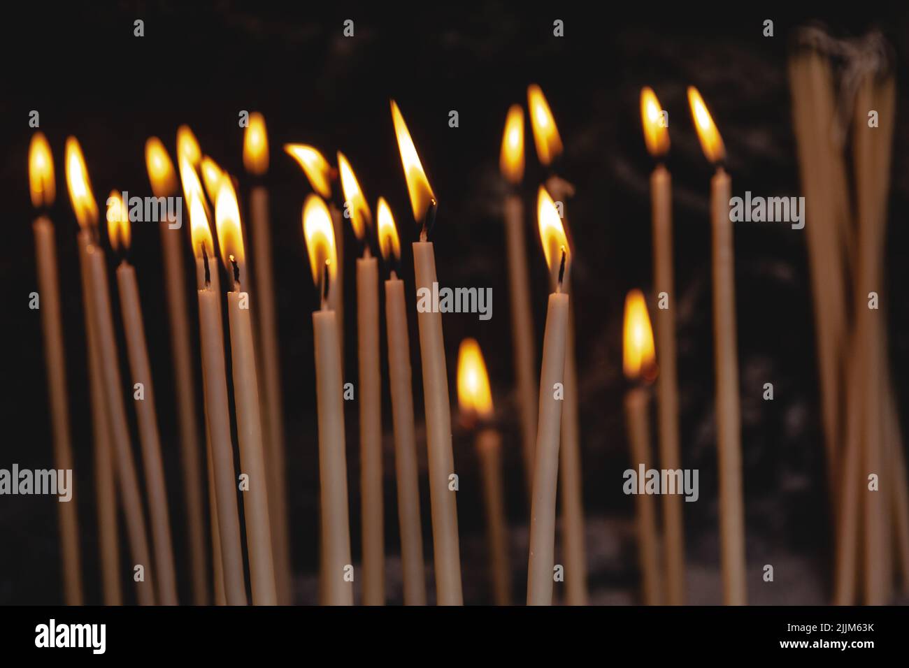 Il bellissimo primo piano di candele bruciate in un luogo religioso Foto Stock