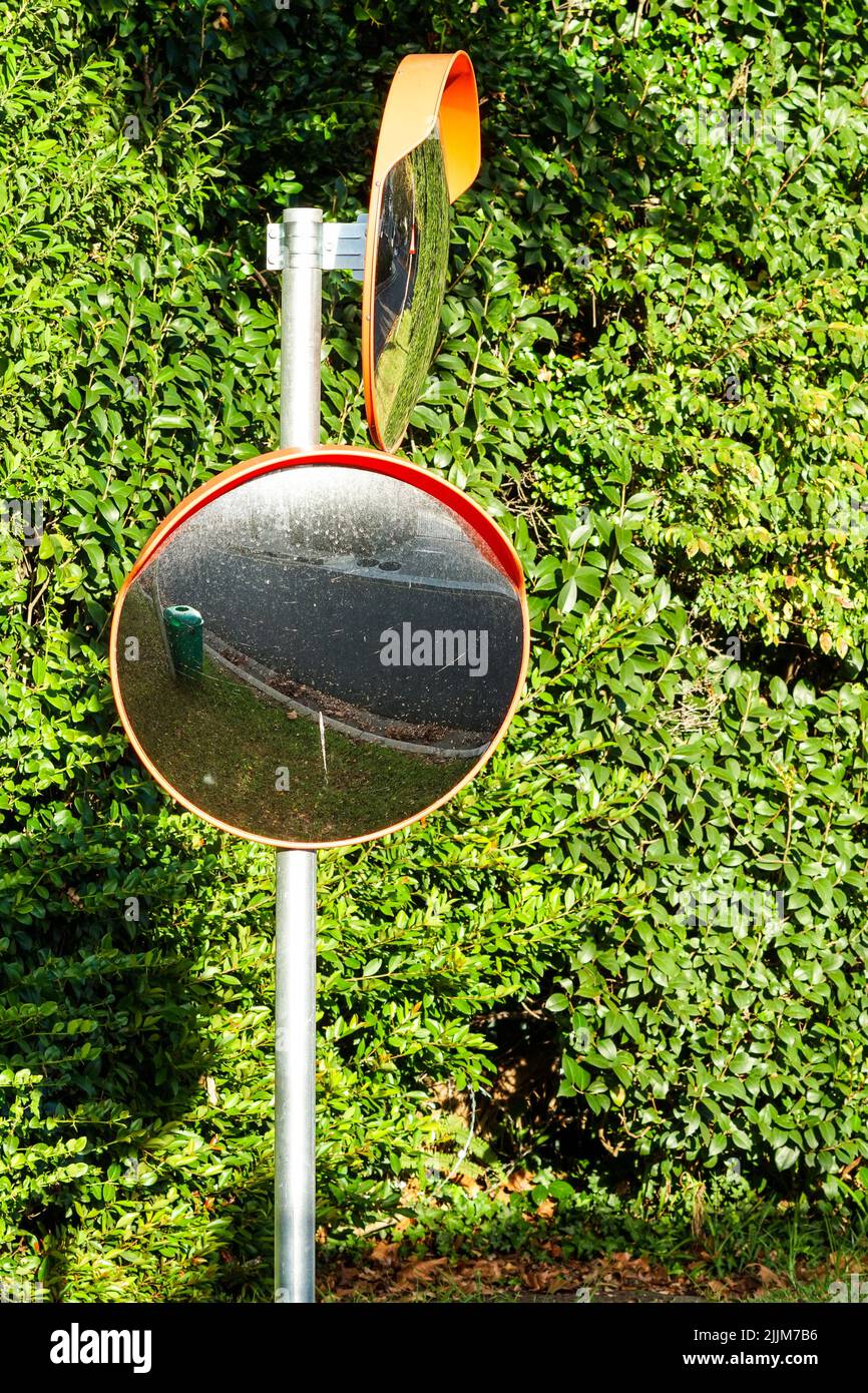 specchio del vialetto montato su un palo in una strada per la copertura dei punti ciechi quando si esce da un concetto di proprietà per la sicurezza del conducente o degli automobilisti Foto Stock