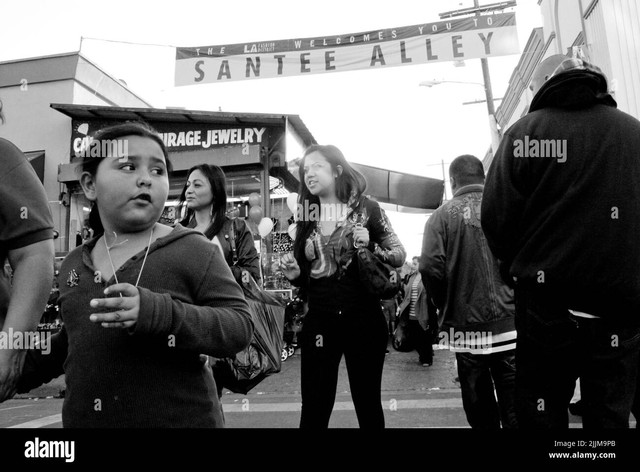 Un fuoco poco profondo della gente casuale che acquista lungo Santee Alley nel centro di Los Angeles in scala di grigi Foto Stock