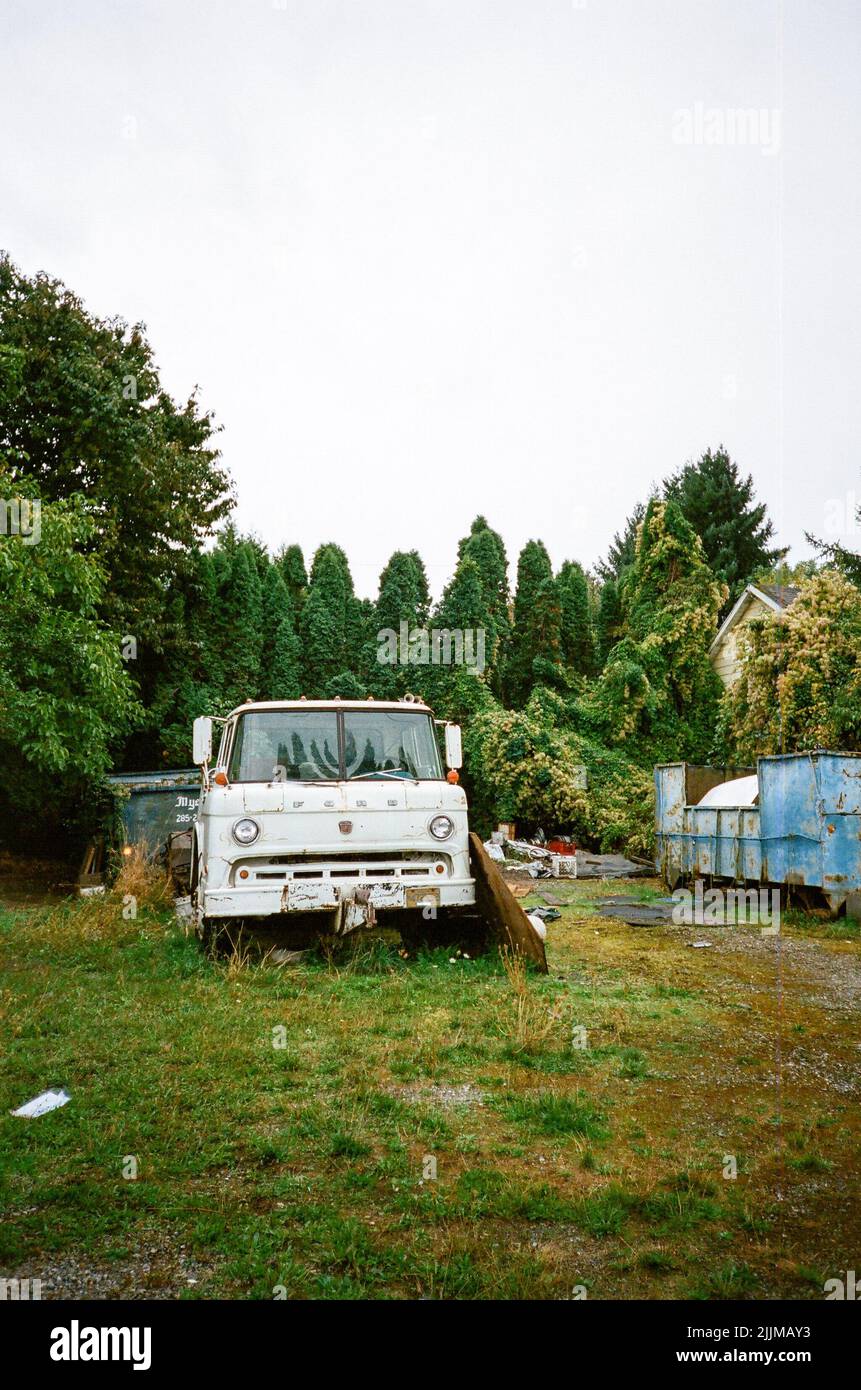 Un'immagine verticale di un semi-camion bianco d'epoca in un cortile circondato da alberi a Portland Foto Stock