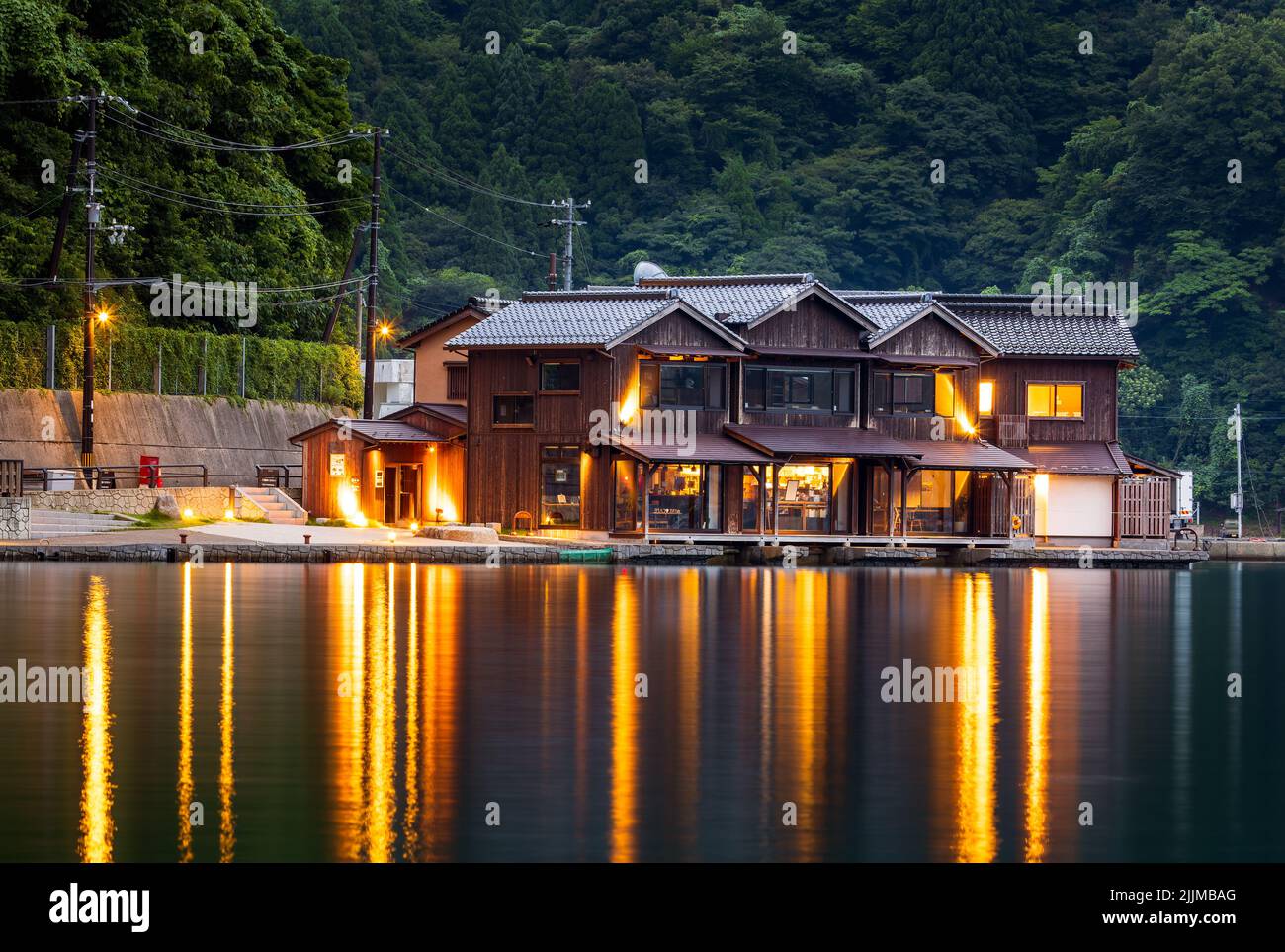 Le luci del ristorante sul lungomare riflettono l'acqua nelle prime ore della sera all'Ine Foto Stock