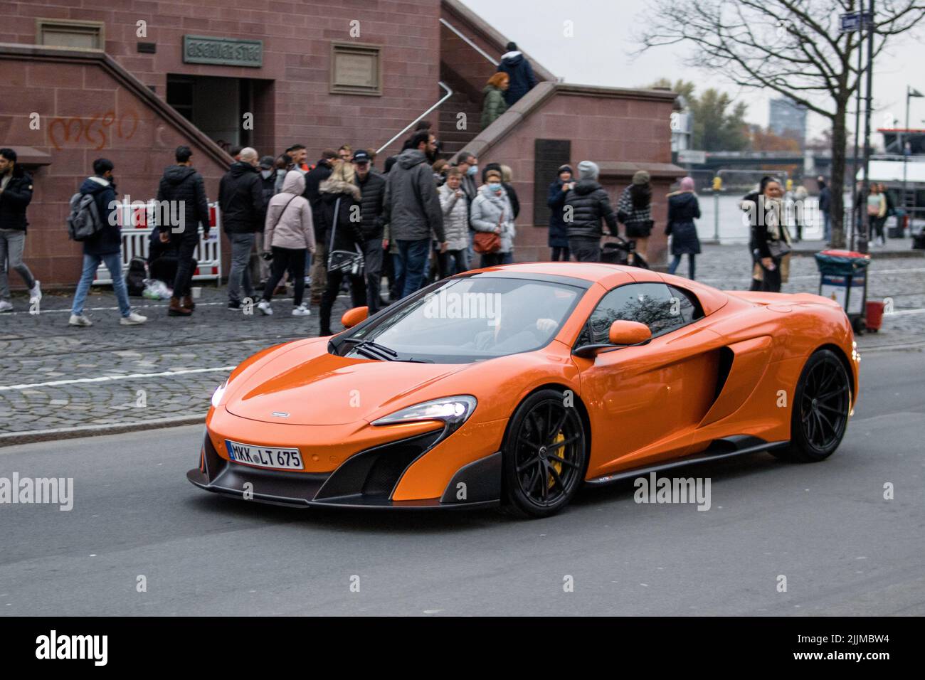 Un bel colpo di una McLaren arancione 650S sulla strada e la gente sullo sfondo Foto Stock