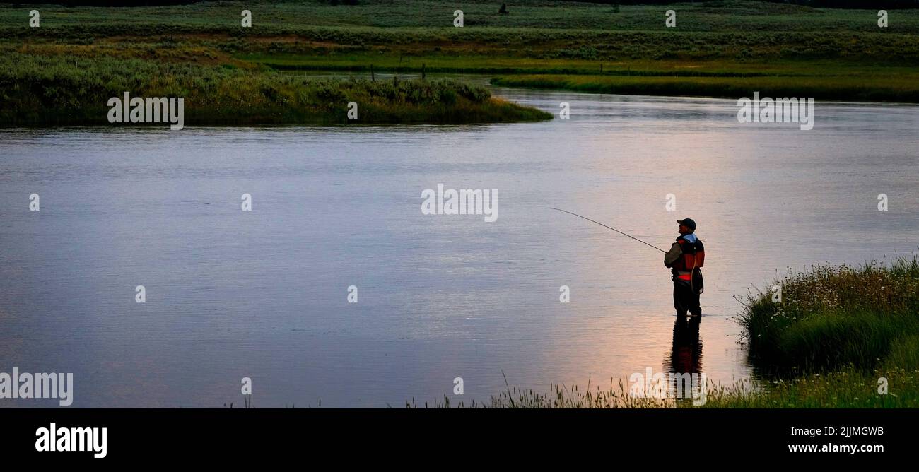 Flyfisherman pescatore a mosca la pesca sul fiume con Tetons in background Foto Stock