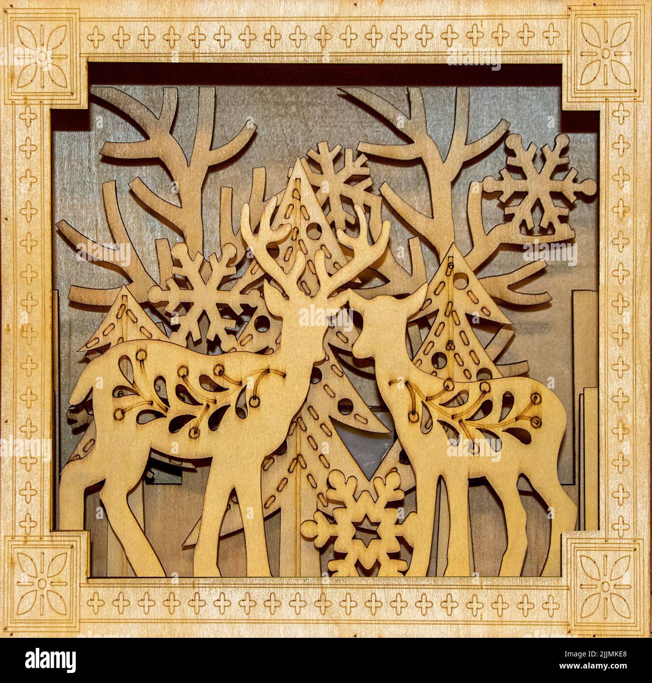 Decorazione natalizia con cervi e alberi e fiocchi di neve - strati tagliati in legno e messi in ombra - grano di legno. Foto Stock