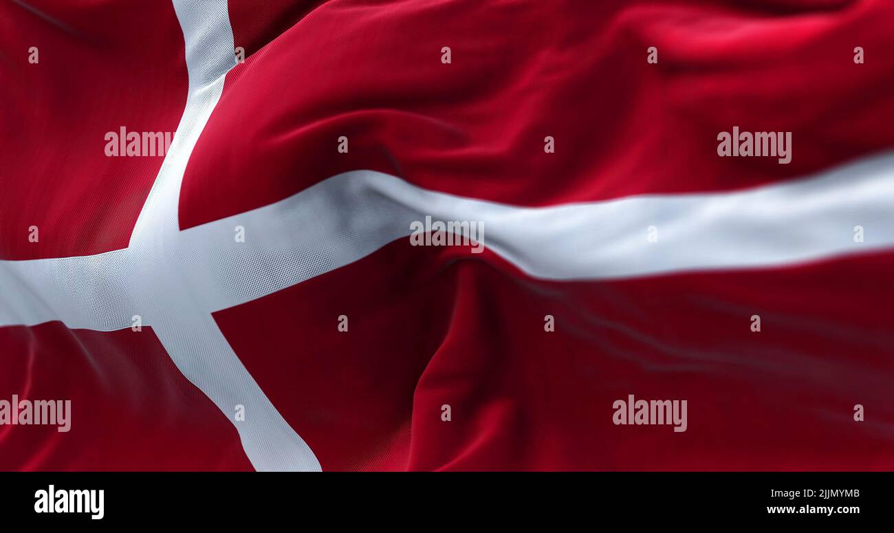 Vista ravvicinata della bandiera danese che sventola nel vento. La Danimarca è un paese nordico dell'Europa settentrionale. Tessuto texture sfondo. Selettivo per Foto Stock