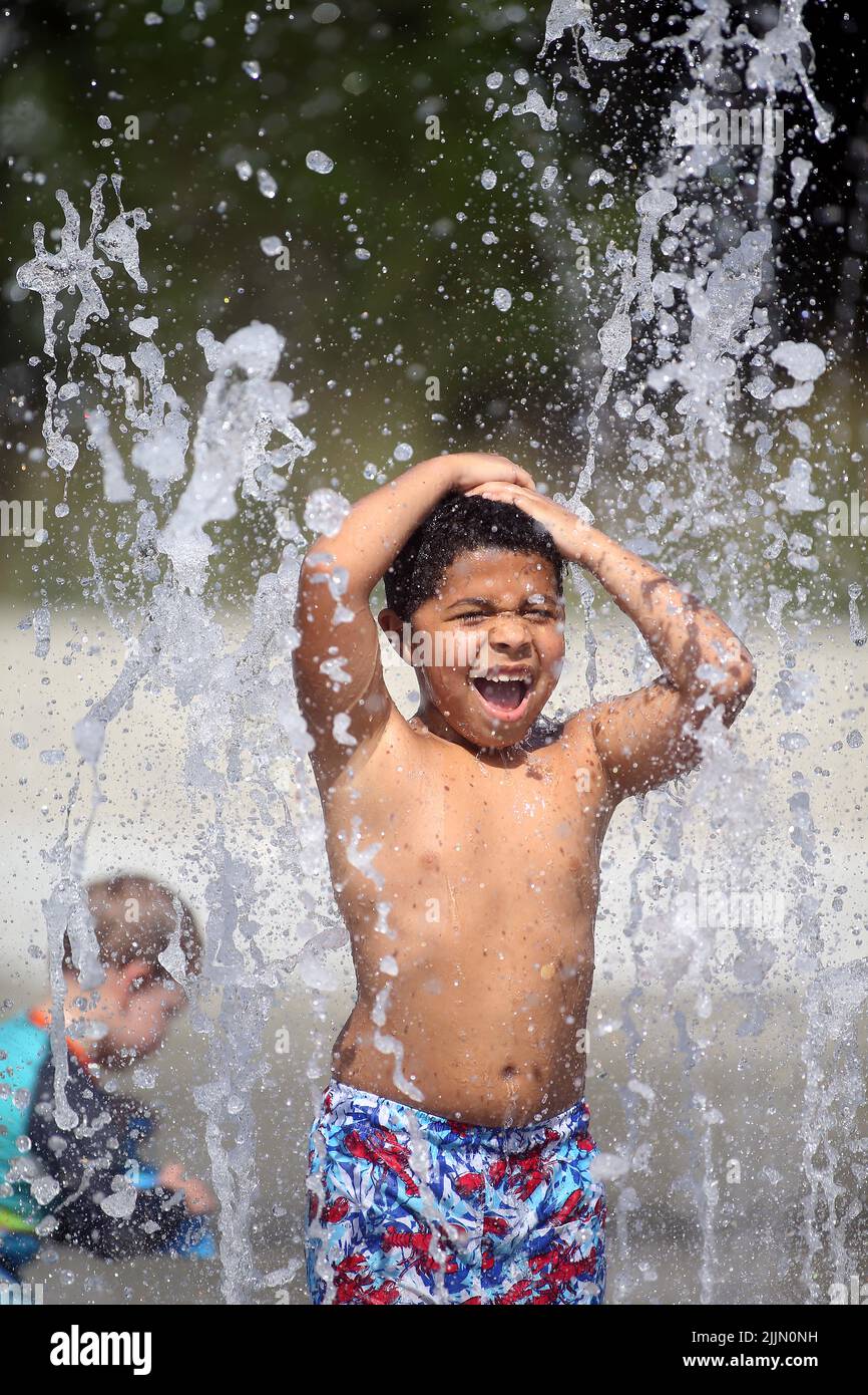 Raleigh, Carolina del Nord, Stati Uniti. 27th luglio 2022. Il VERDE DI AYDEN, risalente a 8 anni fa, si raffredda passando attraverso gli sprinkler a forma di spruzzi nel John Chavis Memorial Park, quando le temperature raggiungeranno nuovamente la metà degli anni '90 a Raleigh, North Carolina. Gran parte del paese ha anche sperimentato temperature superiori alla media per tutto il mese di luglio. (Credit Image: © Bob Karp/ZUMA Press Wire) Foto Stock