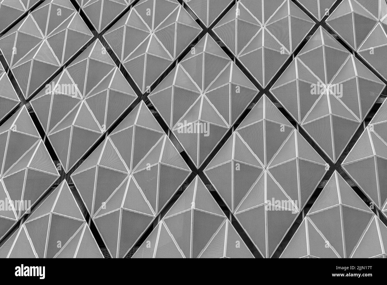 Frammento di un moderno edificio per uffici. Sfondo geometrico astratto. Parte della facciata di un grattacielo con griglie metalliche diamantate. Foto Stock