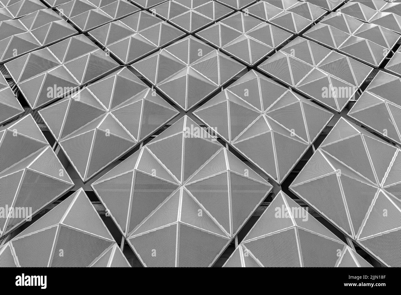 Frammento di un moderno edificio per uffici. Sfondo geometrico astratto. Parte della facciata di un grattacielo con griglie metalliche diamantate. Foto Stock