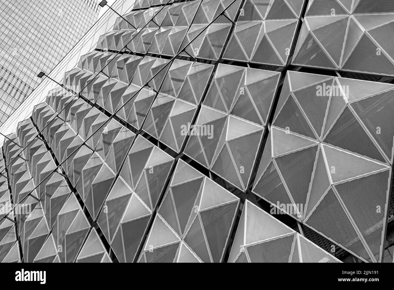 Frammento di un moderno edificio per uffici. Sfondo geometrico astratto. Parte della facciata di un grattacielo con griglie metalliche diamantate. Foto Stock