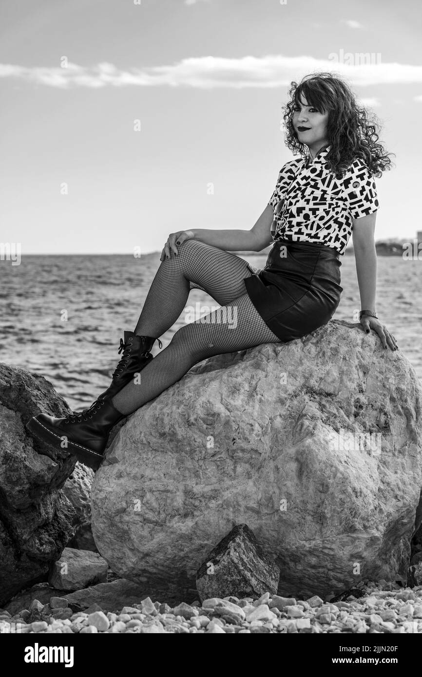 Una donna spagnola alla moda con stile urbano che si posa sul frangiflutti a Malaga, Spagna Foto Stock