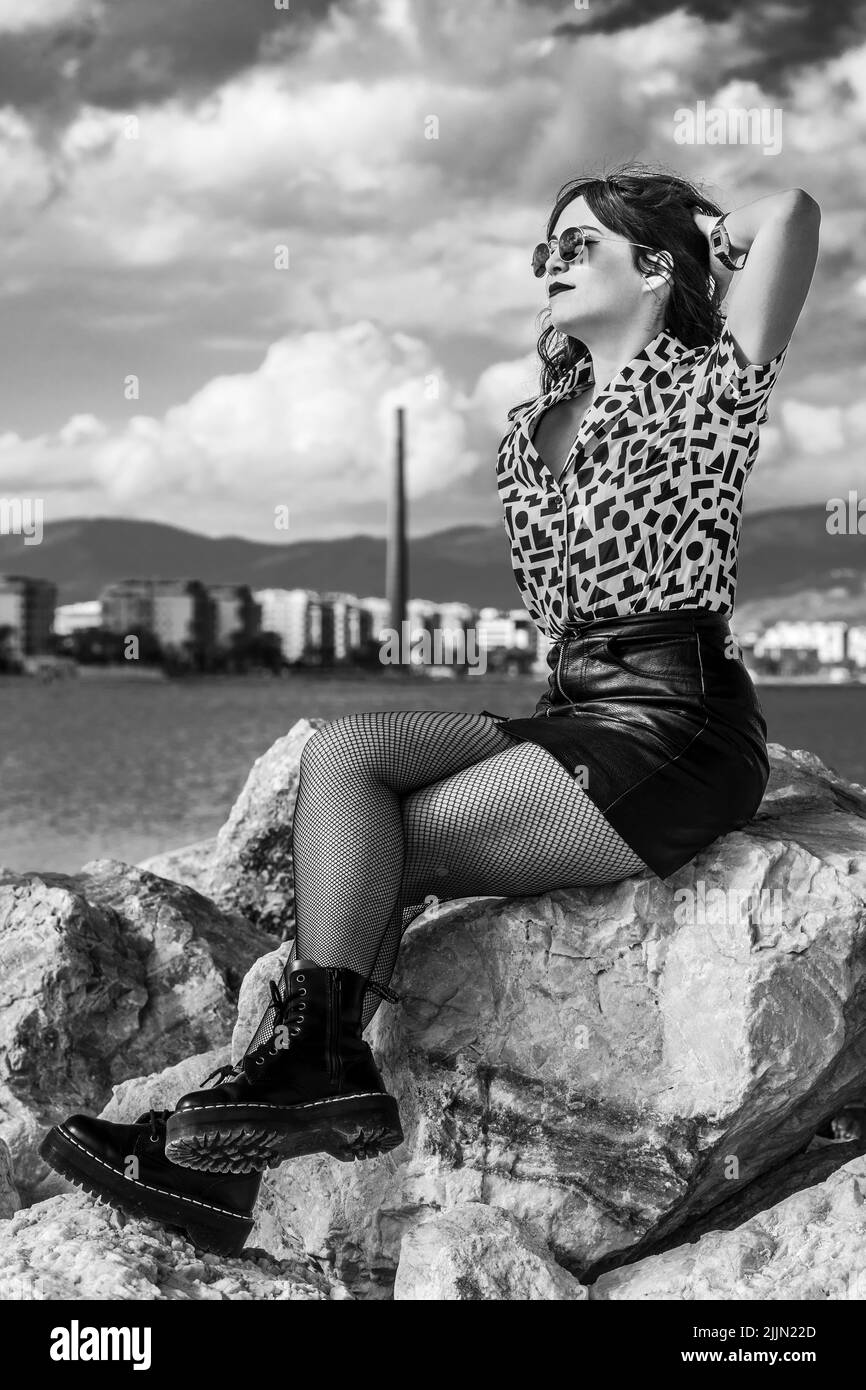 Una donna spagnola alla moda con stile urbano che si posa sul frangiflutti a Malaga, Spagna Foto Stock