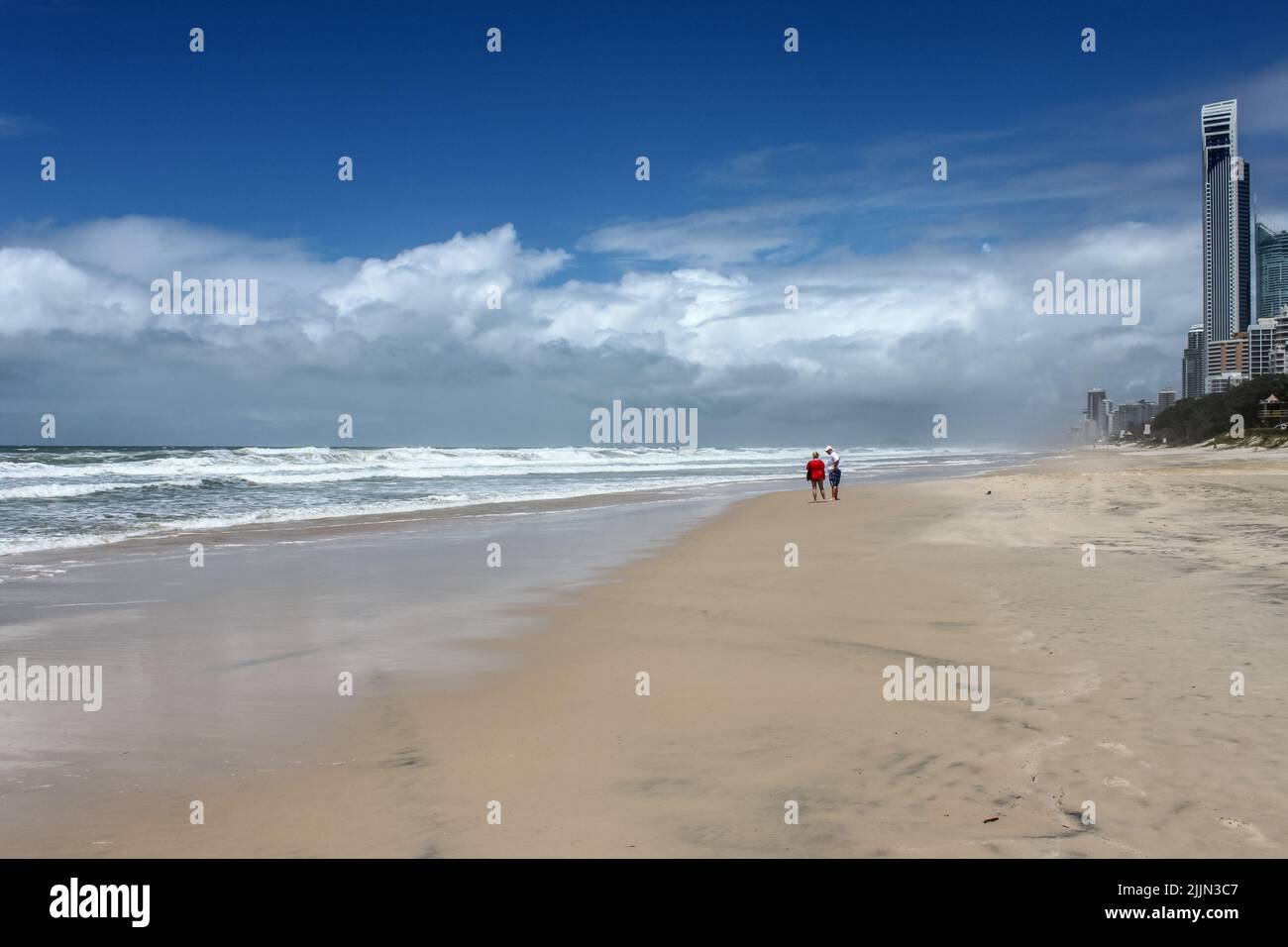 Coppia parlare sulla spiaggia tempestosa con gli edifici di Gold Coast - Surfers Paradise Queensland Australia dietro di loro Foto Stock