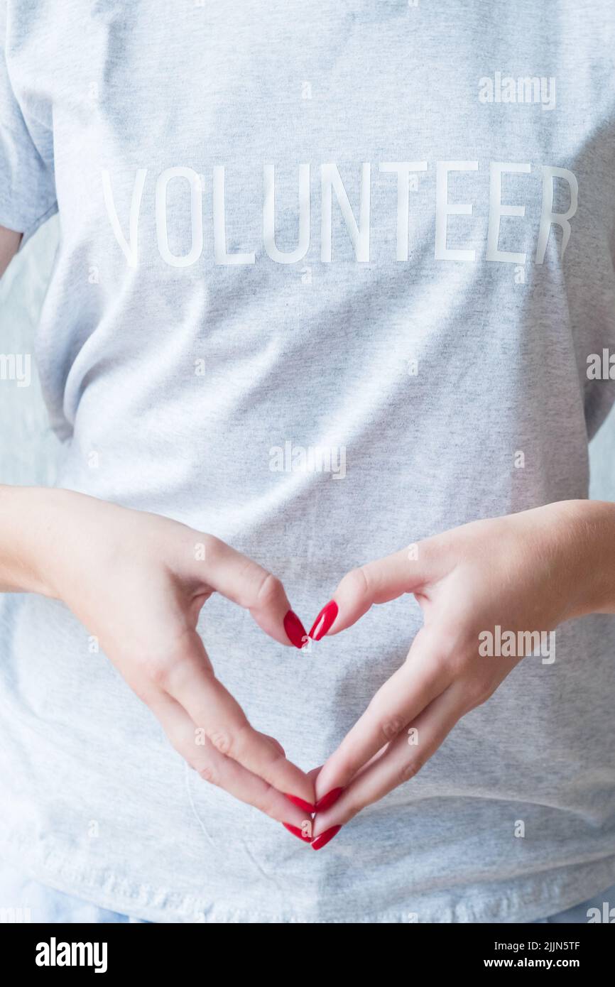 donna grigia t-shirt volontari mani cuore consapevolezza Foto Stock