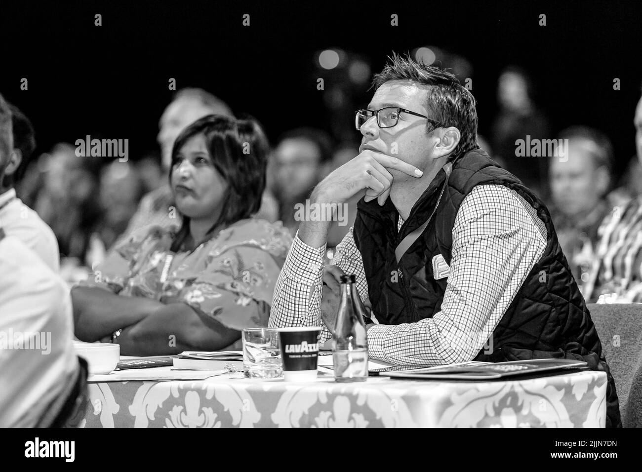 Una scala di grigi di delegati che partecipano a un convegno di vendita in un grande centro congressi a Johannesburg, Sudafrica Foto Stock