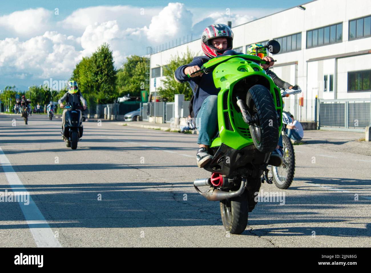 Un motociclista maschile che indossa un casco e fa trucchi con la sua moto sulla strada Foto Stock