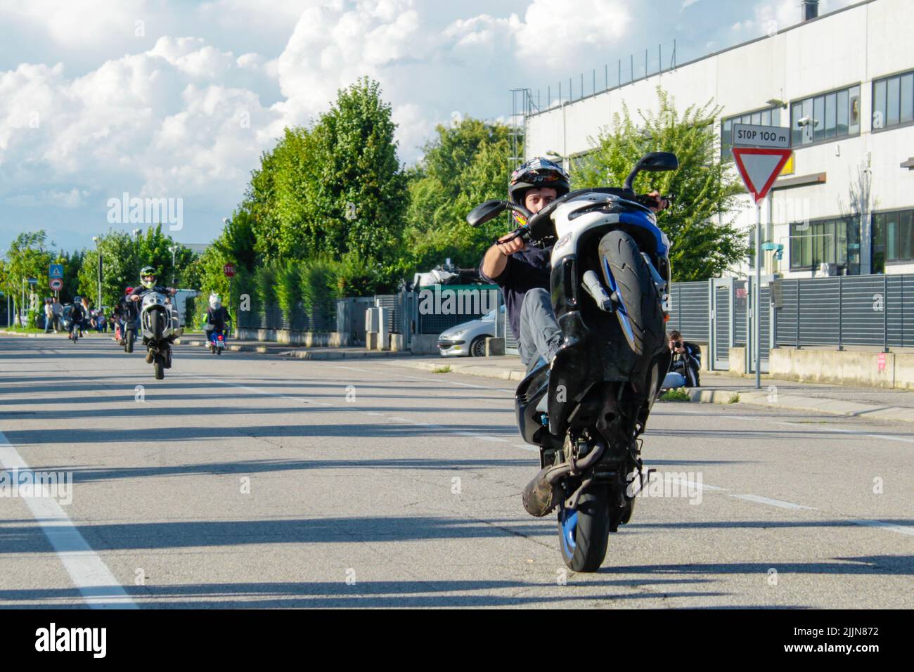 Un motociclista maschile che indossa un casco e fa trucchi con la sua moto sulla strada Foto Stock