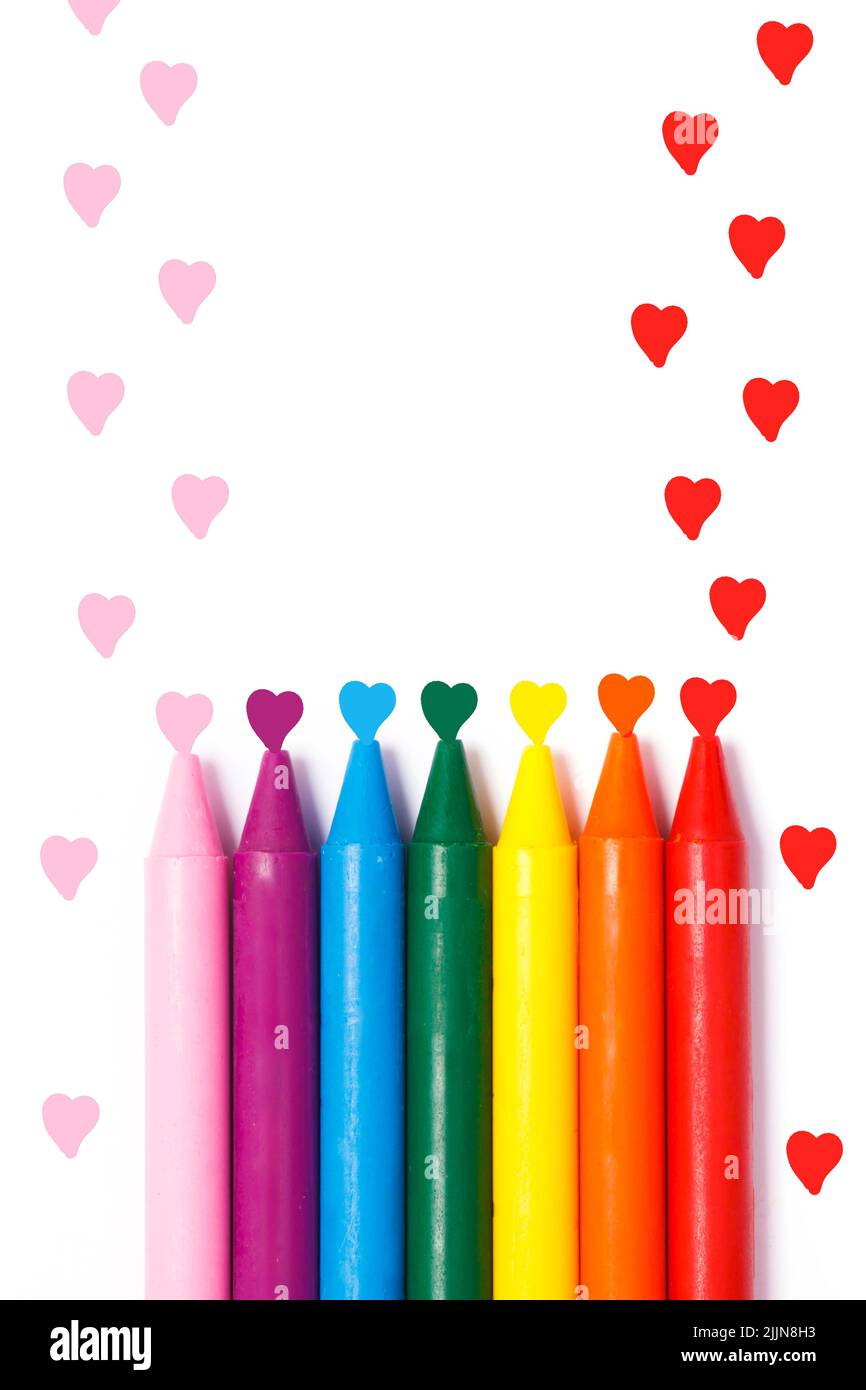 Un colpo verticale di pastelli color arcobaleno con cuori decorativi isolati su sfondo bianco Foto Stock