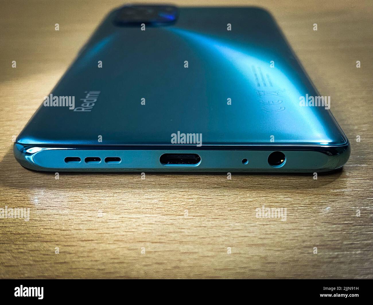 Primo piano di Xiaomi Redmi Note 10 in verde lago sulla scrivania in legno Foto Stock