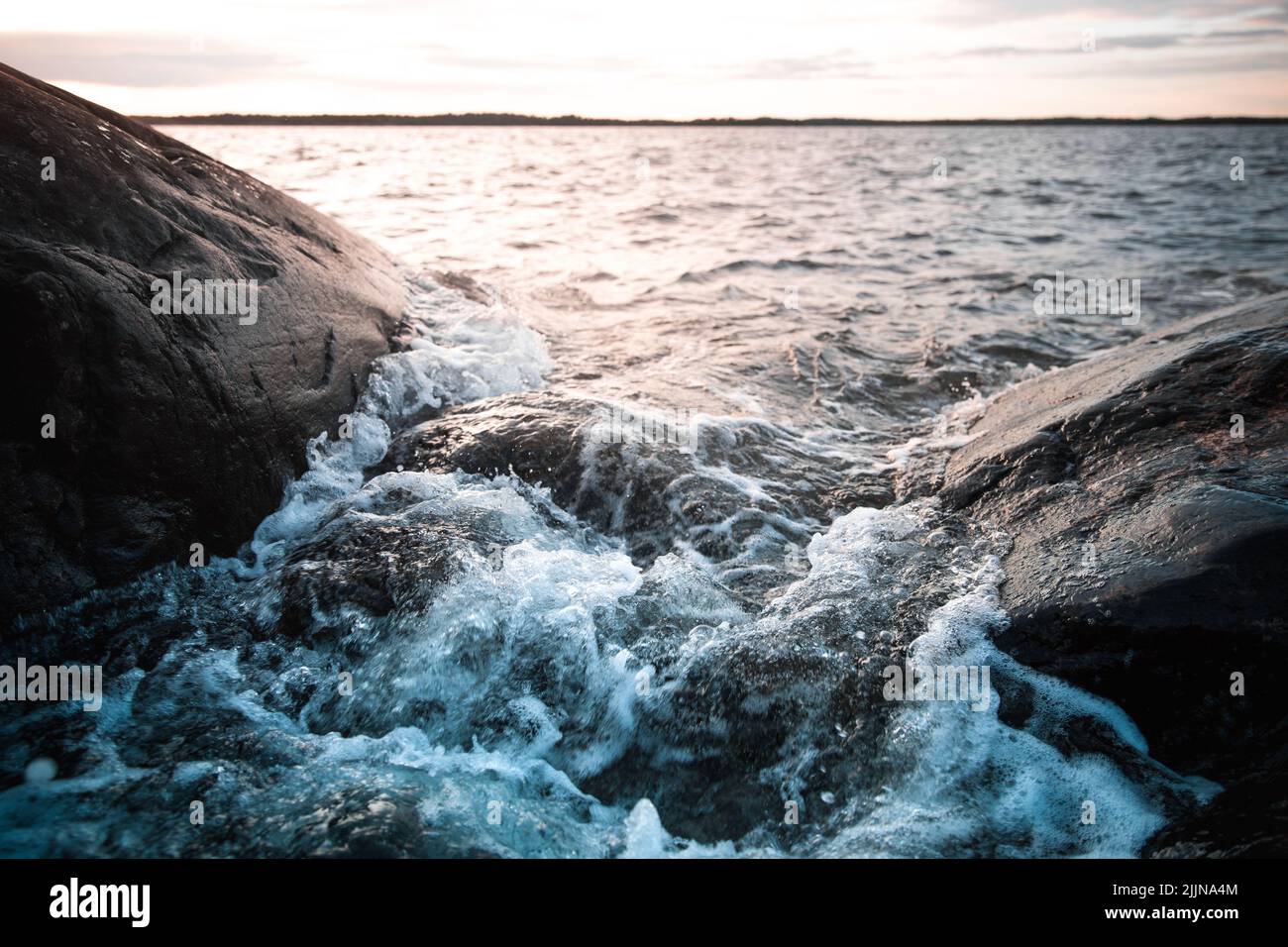 Una vista panoramica delle onde che colpiscono la riva sul mare al tramonto Foto Stock