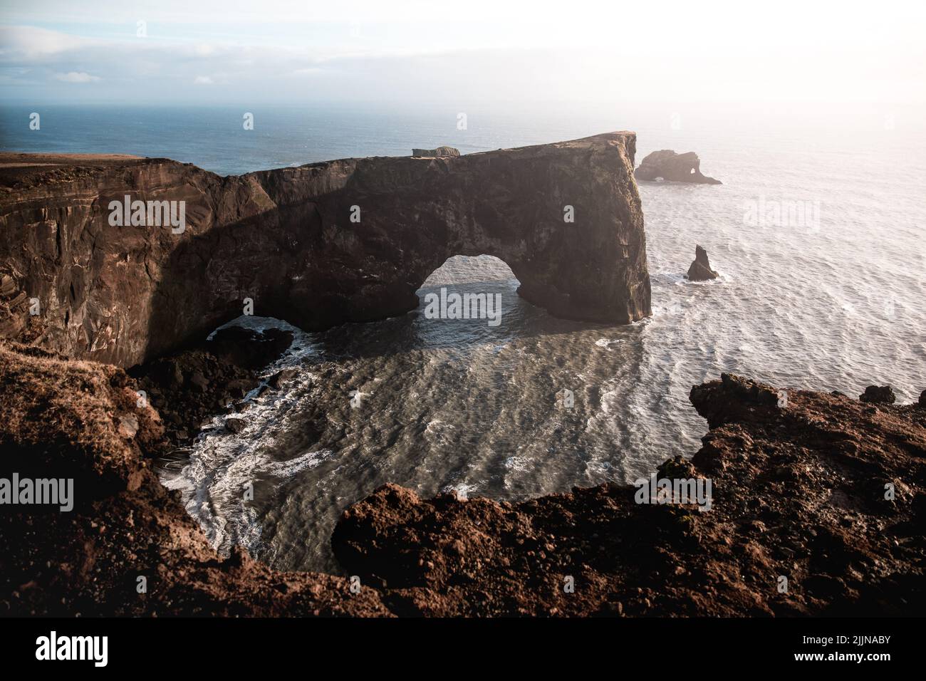 Una vista panoramica della penisola di dyrholaey contro il cielo blu nella luce del sole nel sud dell'Islanda Foto Stock