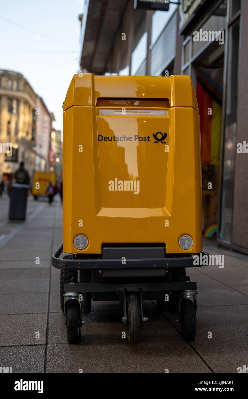 Una bella foto di un carrello di consegna Deutsche Post giallo in una strada trafficata a Dortmund, Germania Foto Stock