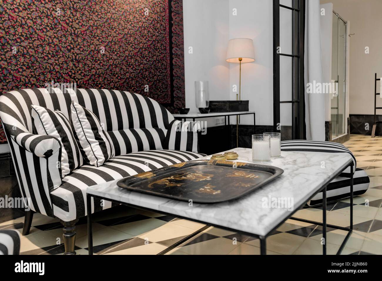 Un piccolo soggiorno in stile eclettico con un divano-tavolino da caffè e una lampada di sottofondo. Foto Stock