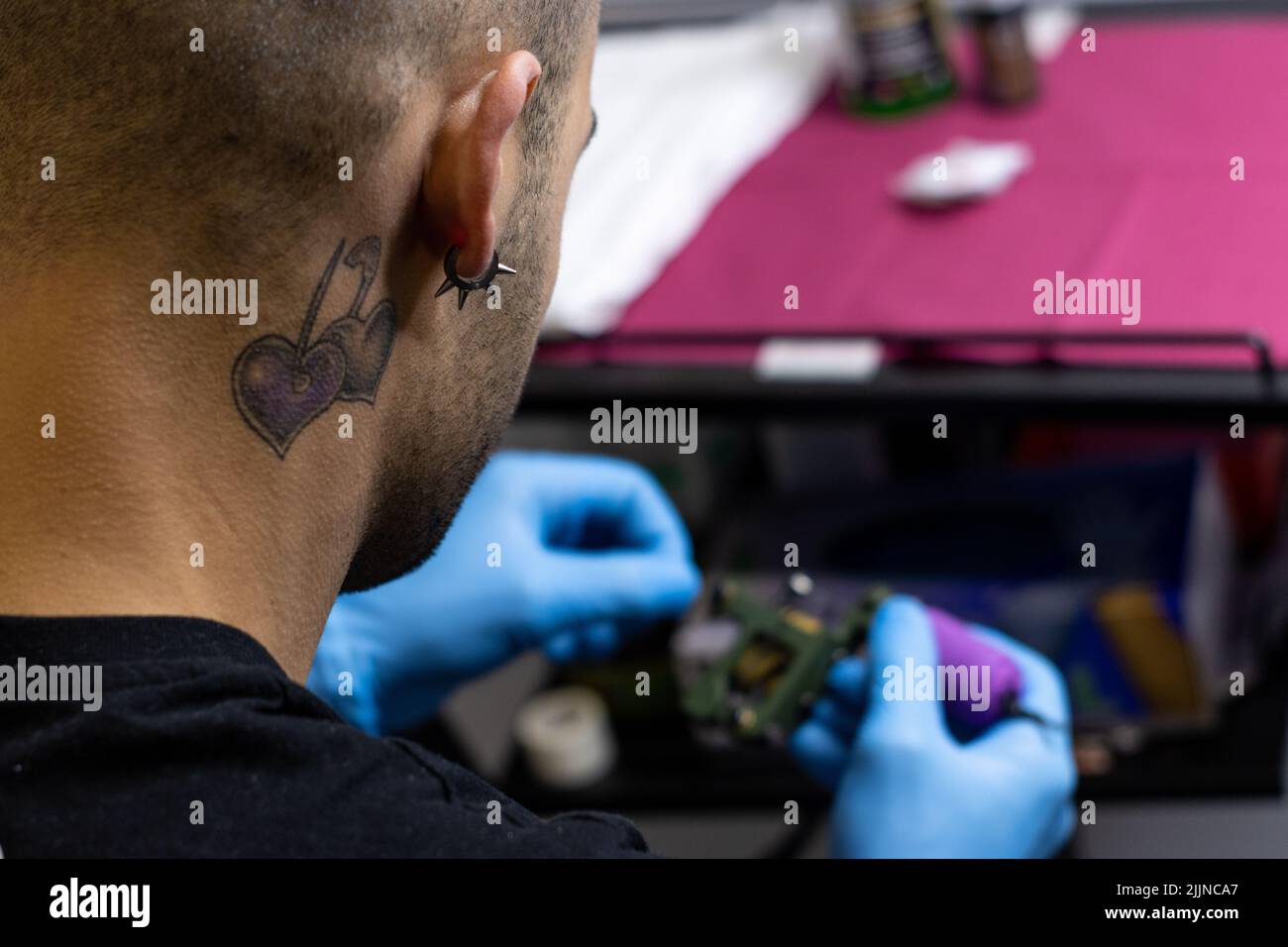 Ritratto di un tatuatore caucasico professionista che prepara la pistola da tatuaggio o la macchina da tatuaggio prima di eseguire un tatuaggio Foto Stock