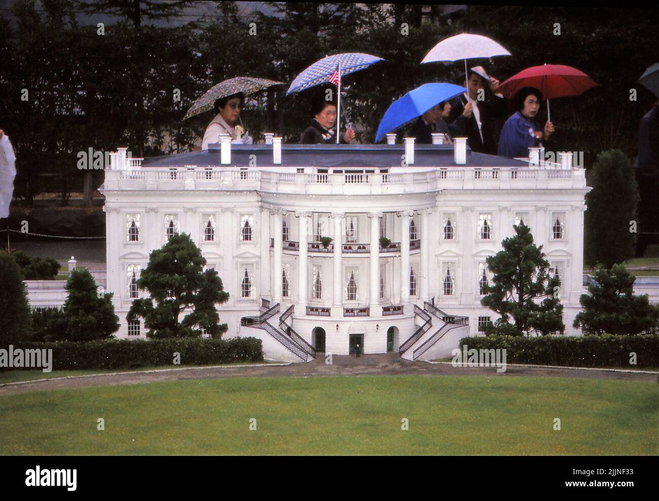 I turisti camminano oltre il modello della Casa Bianca di Tobu World Square mentre tengono l'ombrello Foto Stock