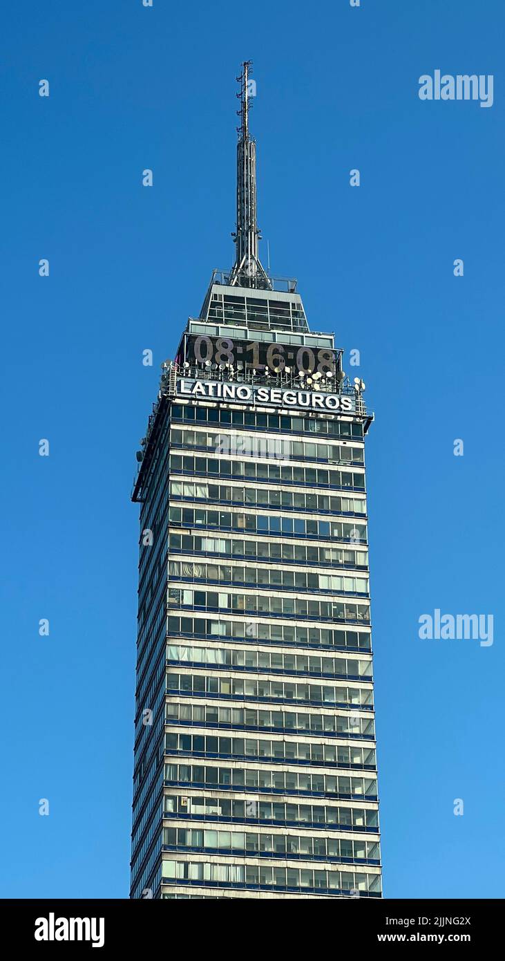 Un colpo verticale della torre latino-americana con un orologio e un segno 'LATINO SEGUROS' in Messico Foto Stock