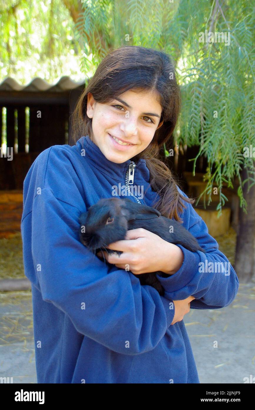 Sorridendo ragazza adolescente coccolare un coniglio animale domestico Foto Stock