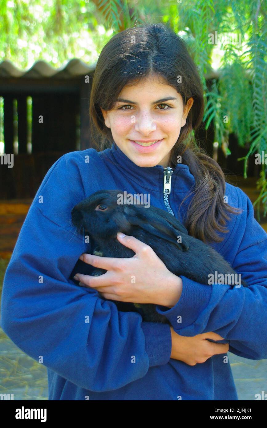 Sorridendo ragazza adolescente coccolare un coniglio animale domestico Foto Stock